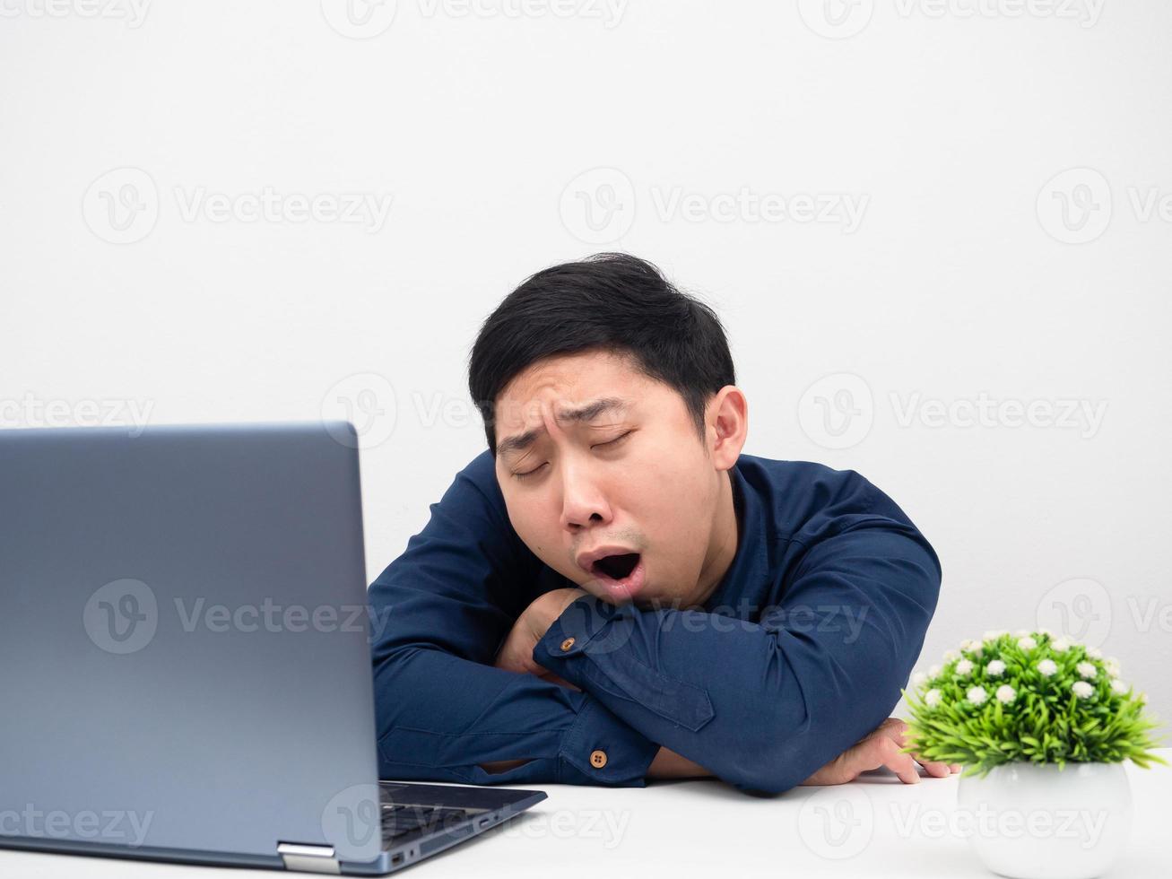 Man gesture yawn feeling sleepy tried from working with laptop on the table photo