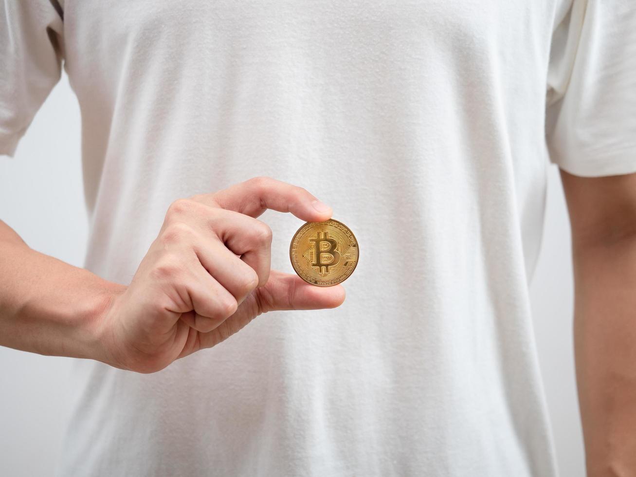 Close up man white shirt show golden bitcoin in his hand photo