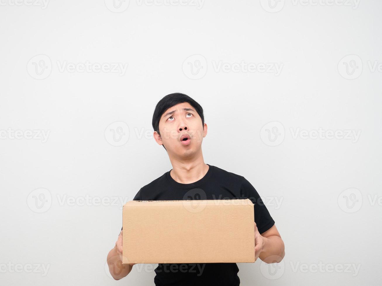 Man holding parcel box feeling amazed looking up at copy space photo