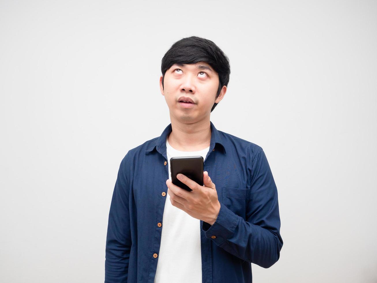 Asian man holding mobile phone and feeling bored gesture looking up white background photo