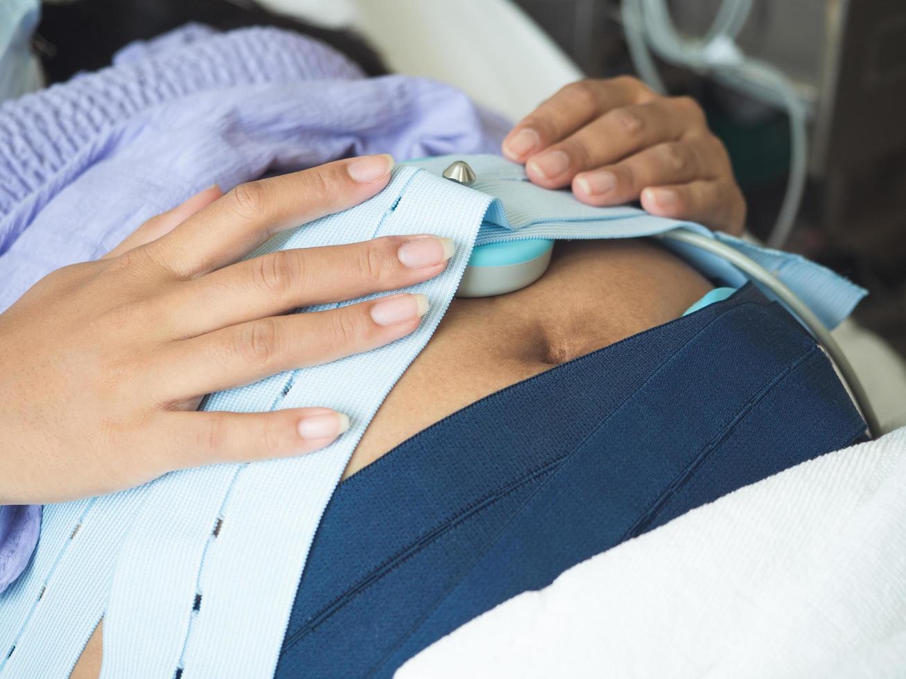 concéntrese embarazada en la cama revisando al bebé con equipo médico en el hospital foto
