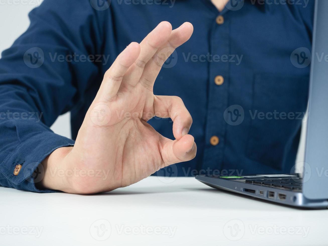 Close up man gesture hand ok on the table with laptop in working room photo