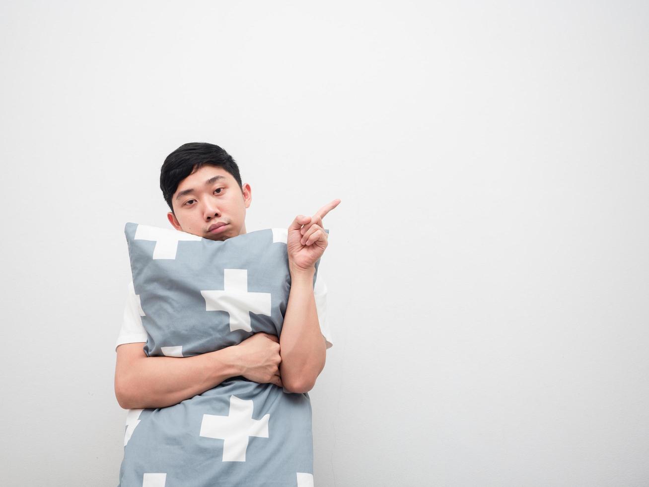 Lazy man hug pillow point finger at space sleepy face white background photo