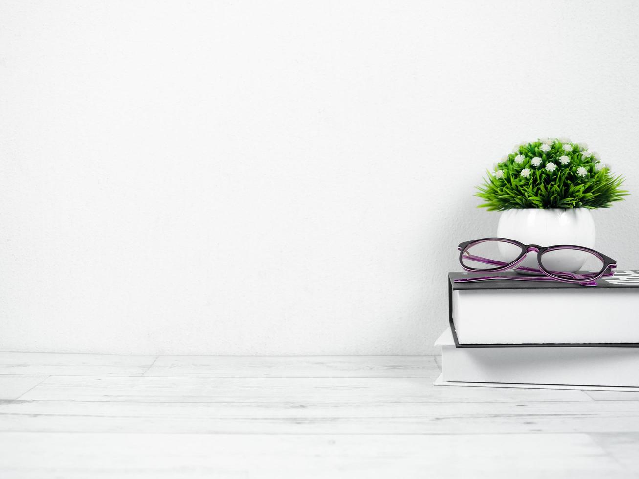 Glasses on the books with small vase on the desk workspace at home copy space photo