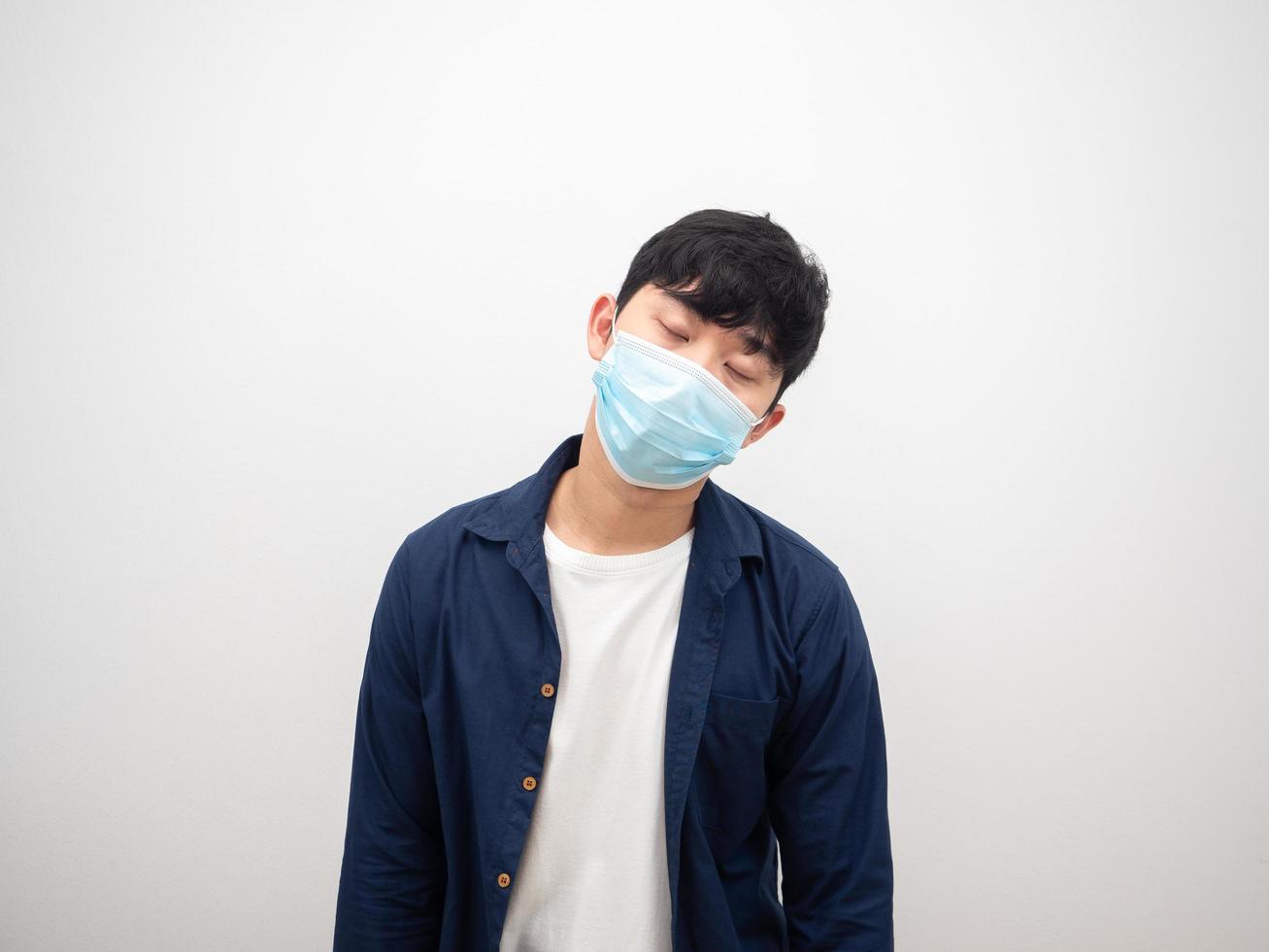 hombre asiático con máscara protectora enfermo y ojos cerrados se siente mal con fondo blanco foto