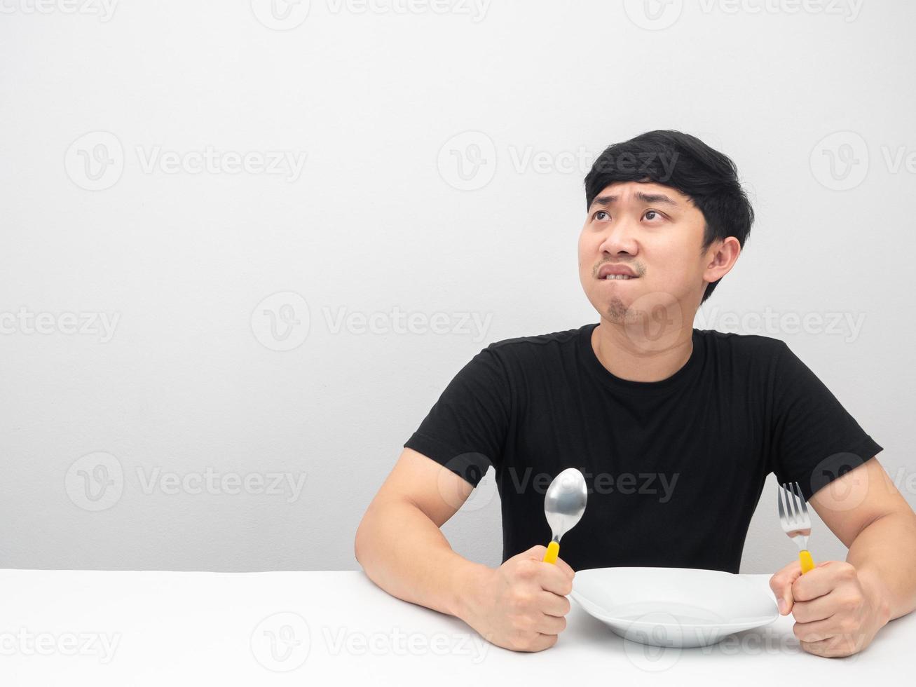 hombre sosteniendo cubiertos sintiéndose muy hambriento y mirando el espacio de copia blanco aislado foto