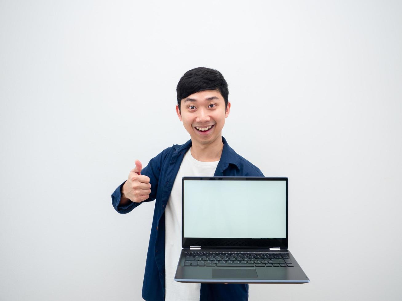 Asian cheerful man show laptop white screen in hand and thumb up looking at camera on white isolated background photo