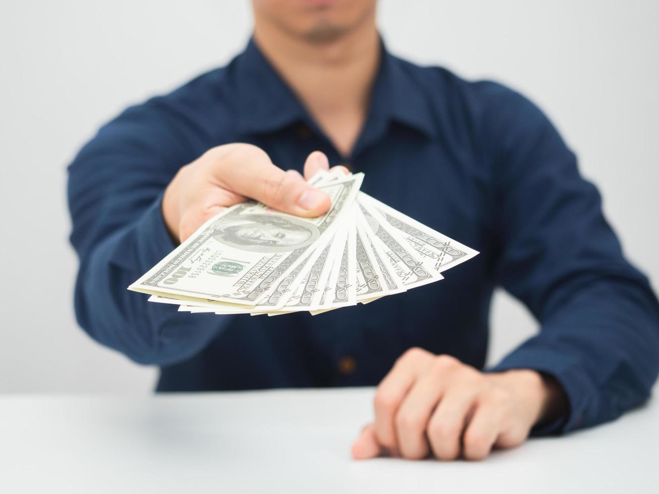 Closeup man hand giving money dollar to you earn salary concept photo