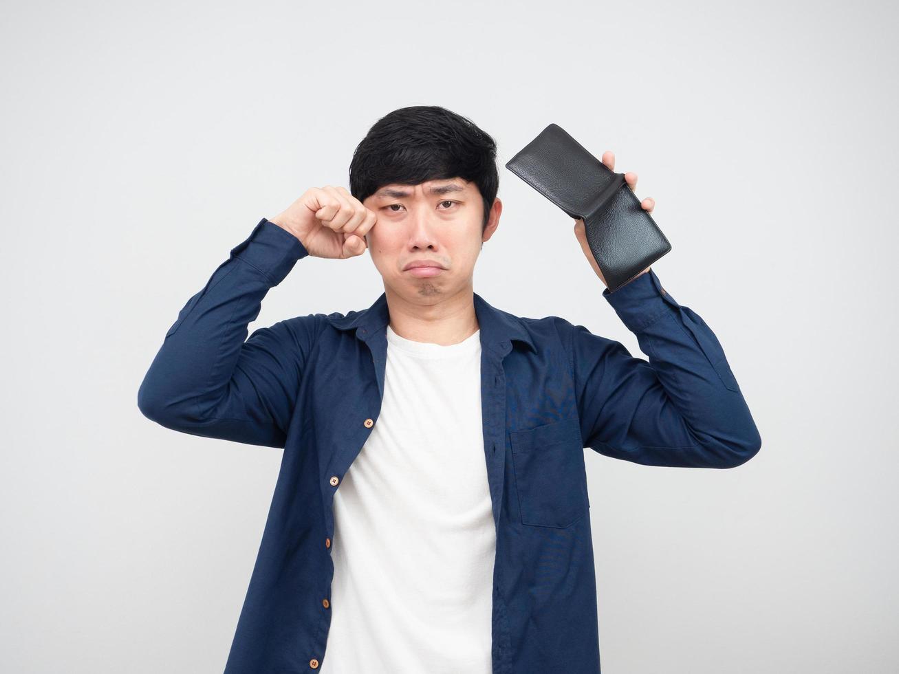 hombre asiático llorando y sosteniendo una billetera vacía en la mano retrato de fondo blanco foto