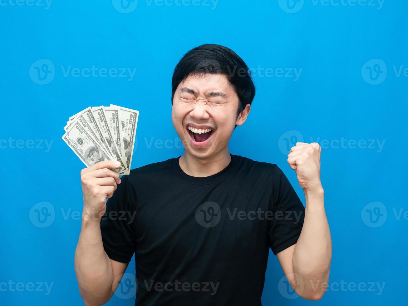 Man feeling happy holding money show fist up blue background photo