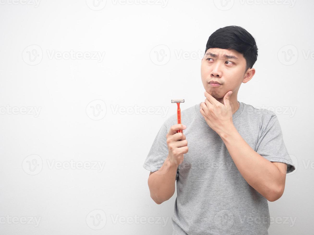 Asian man holding shaving gesture thinking and looking at copy space photo