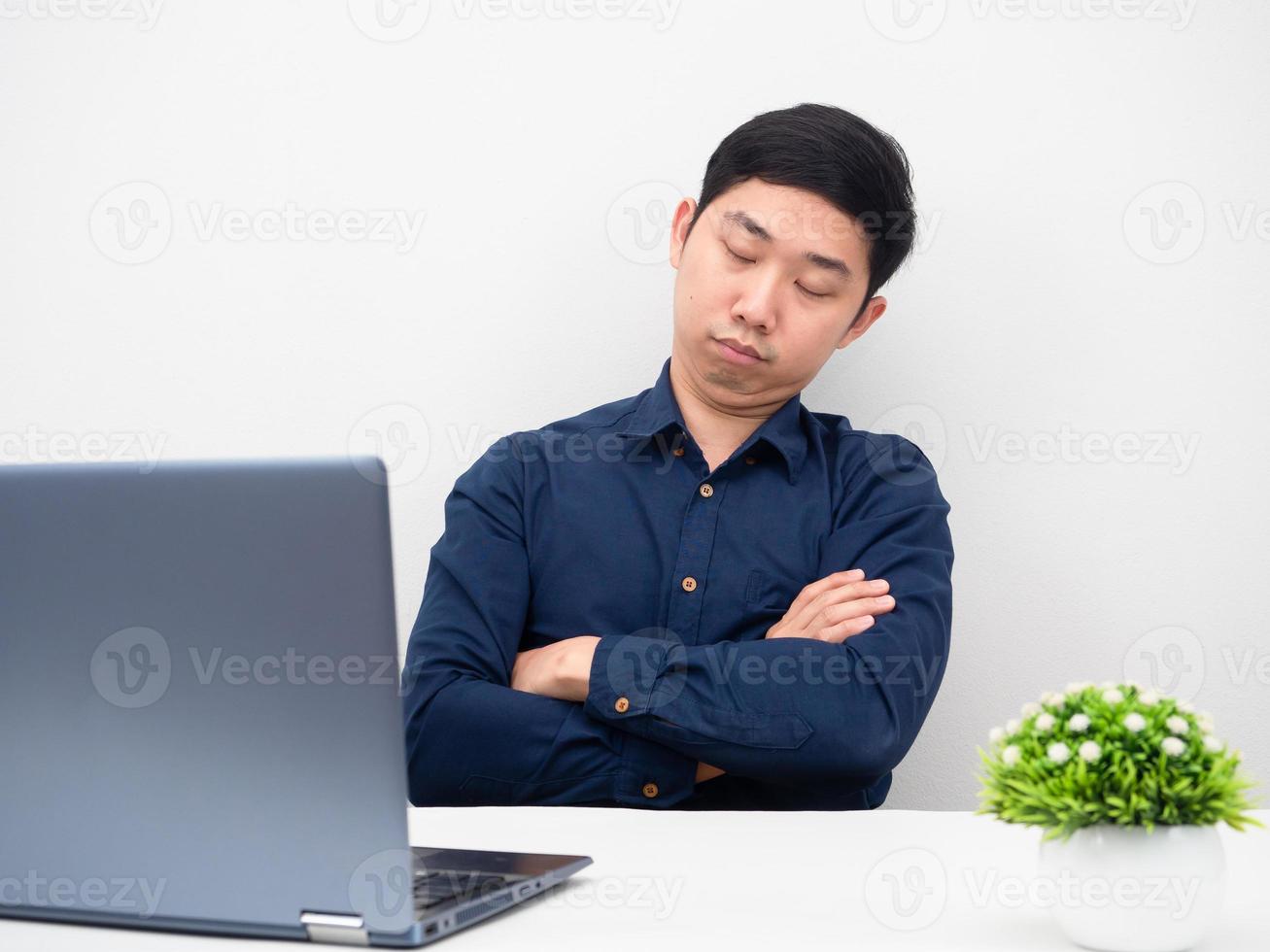 Man sitting cross arms at his workplace sleeping with laptop on the table photo