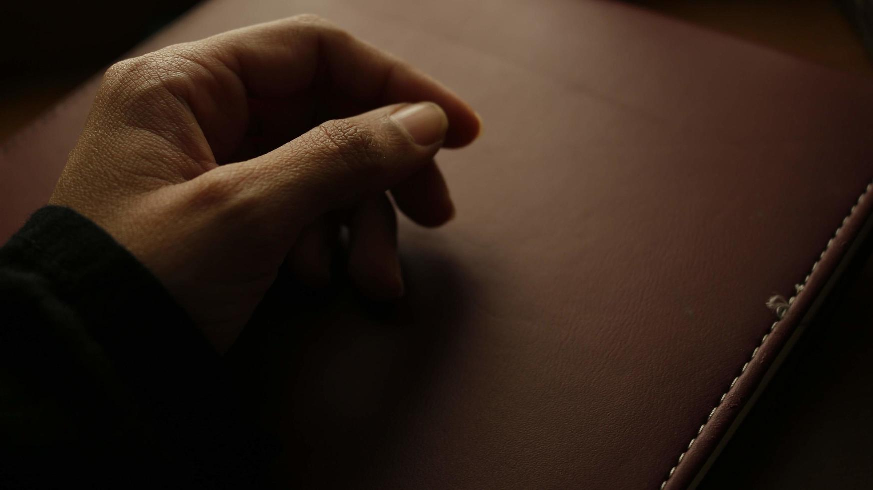 primer plano de la mano de una mujer en un libro en un ambiente sombrío foto