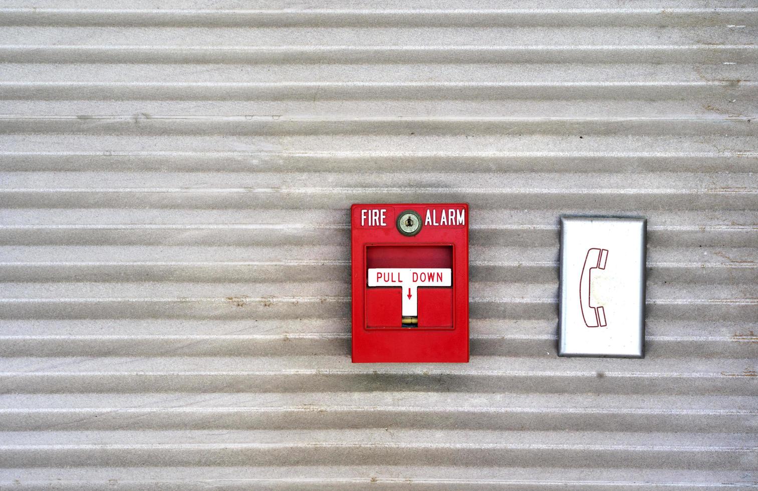 la alarma contra incendios roja está pegada a la pared y al muro de cemento de la fábrica para ser utilizada como sistema de alerta cuando hay un incendio. foto