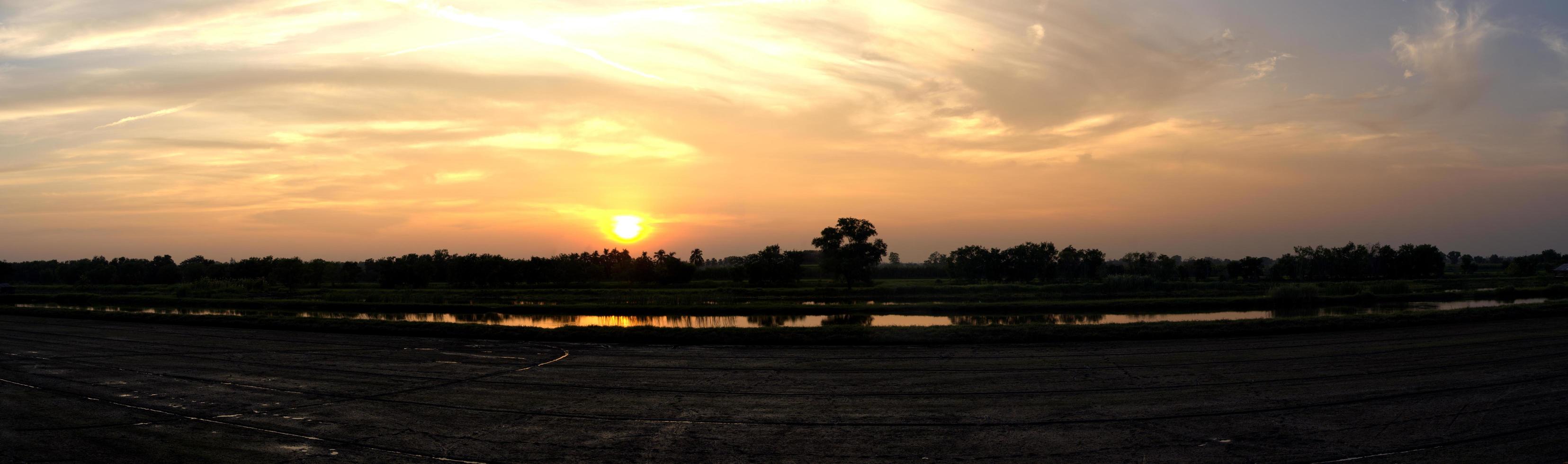 las nubes amarillas del cielo de los rayos del sol están a punto de ponerse, fotografía de la puesta de sol en el campo por la noche, vista panorámica de los campos de arroz, tailandia foto