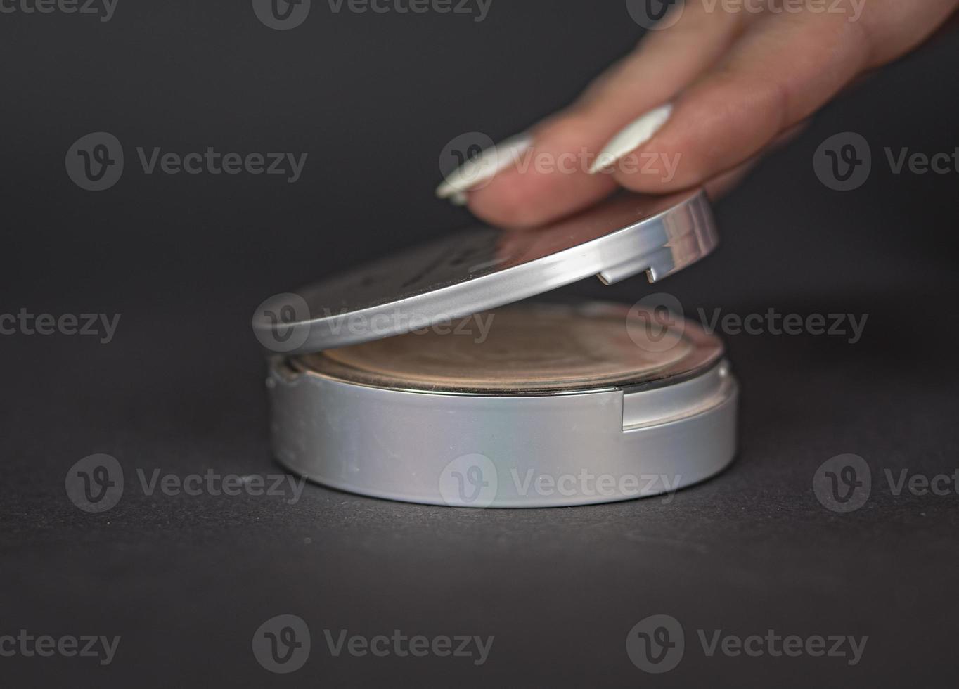 Powder in a round box of light gray color on a dark gray background photo