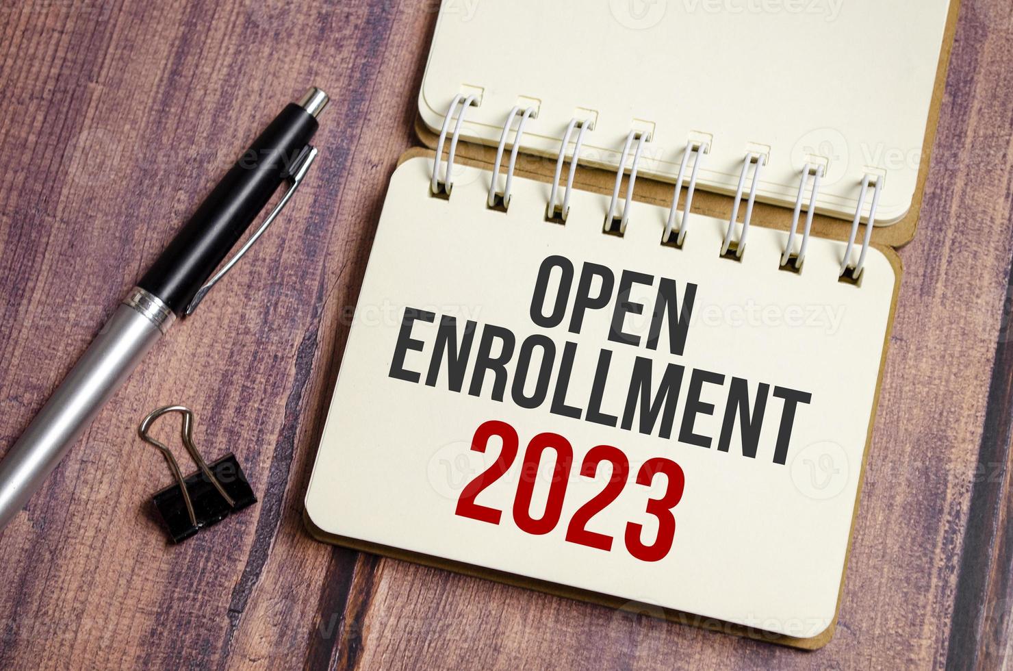 OPEN ENROLLMENT 2023 words on notebook with pen and clips photo