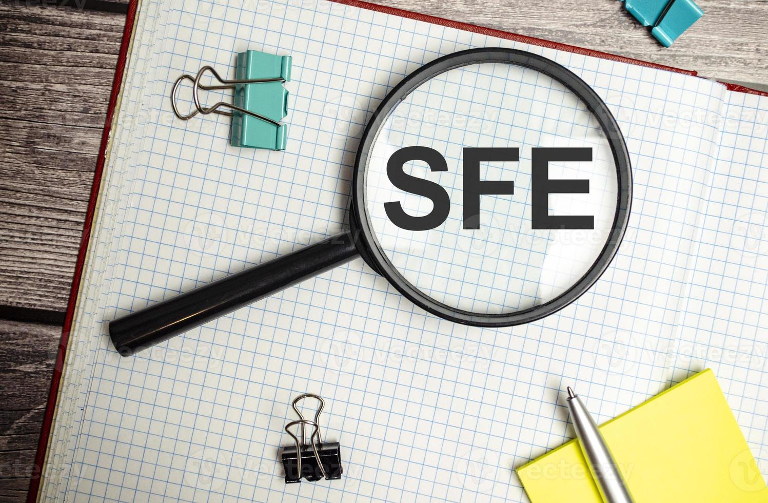 Concept image of Accounting Business Acronym SFE Sales Force Effectiveness written on white notebook with magnifying glass photo