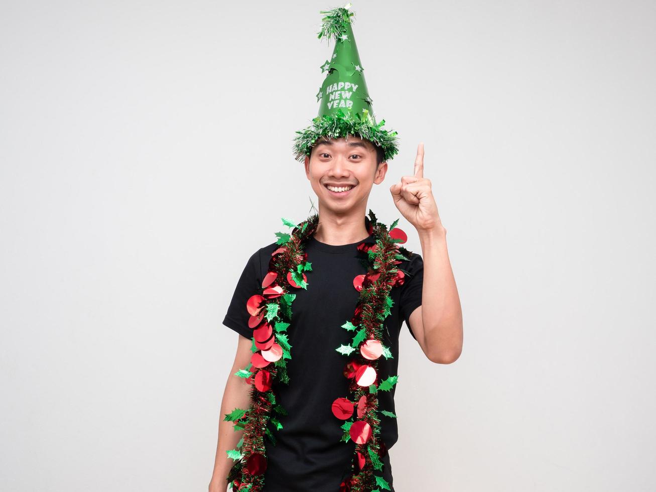 Portrait young man happy face with green hat and tassel colorful point finger above look at camera and smile on white isolated background photo