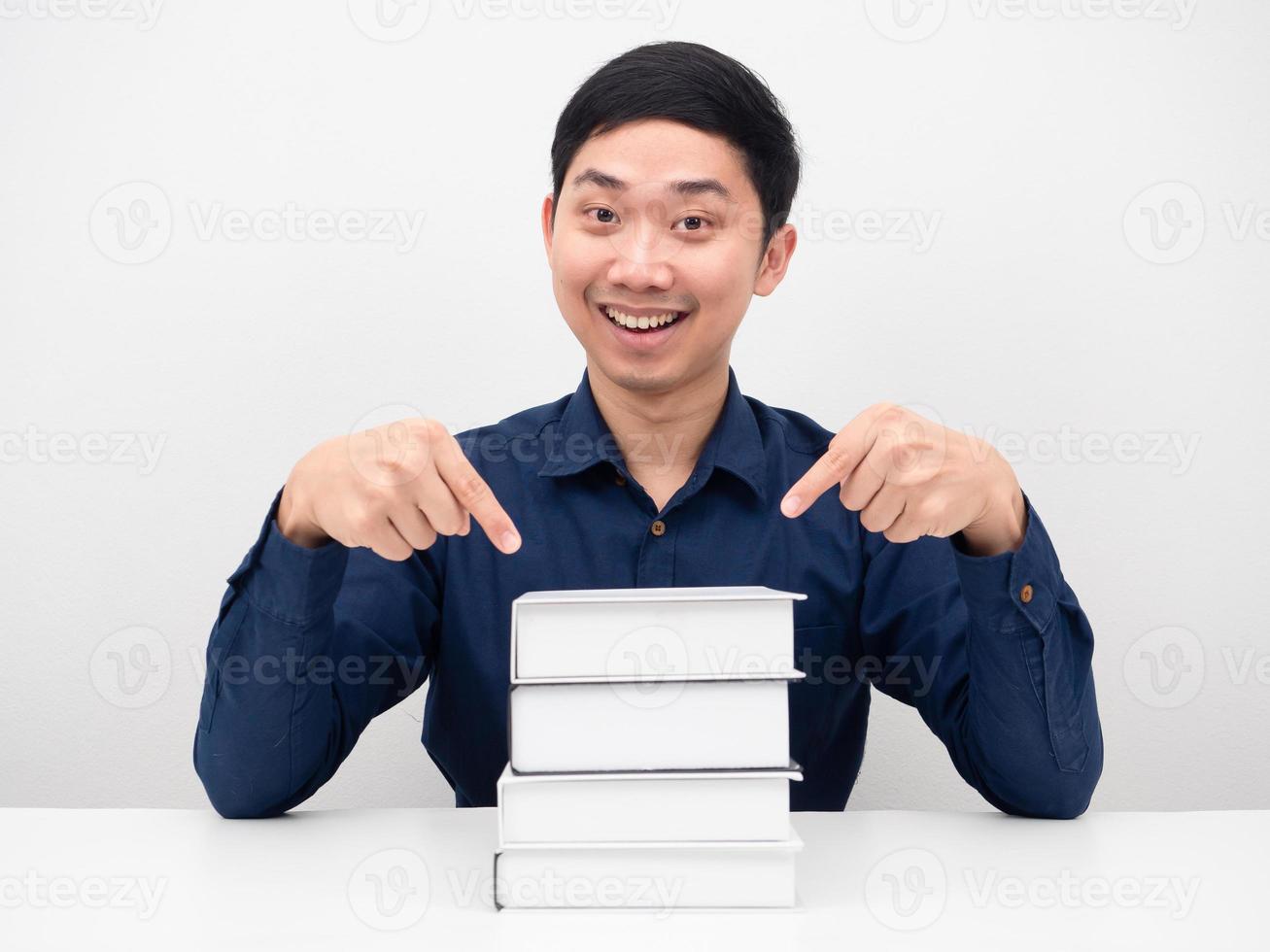 Cheerful man smile and point finger at the books on the table photo