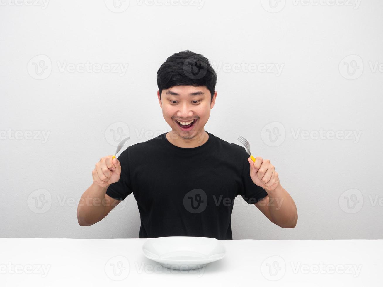 Man hungry holding cutlery gesture ready to eatting dinner on the table photo