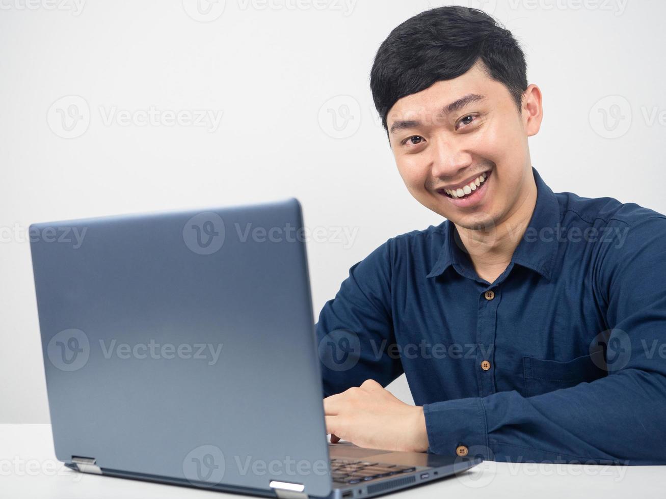 hombre alegre sonriendo sentado con una laptop en el espacio de trabajo de la oficina foto