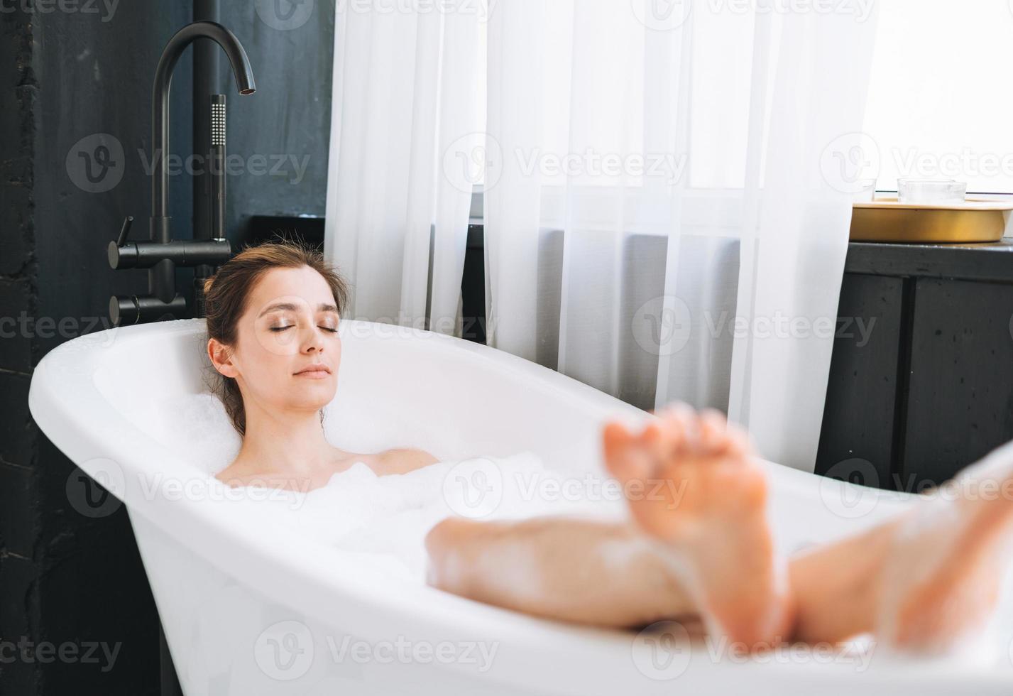Young happy woman taking bath with foam at home, treat yourself photo