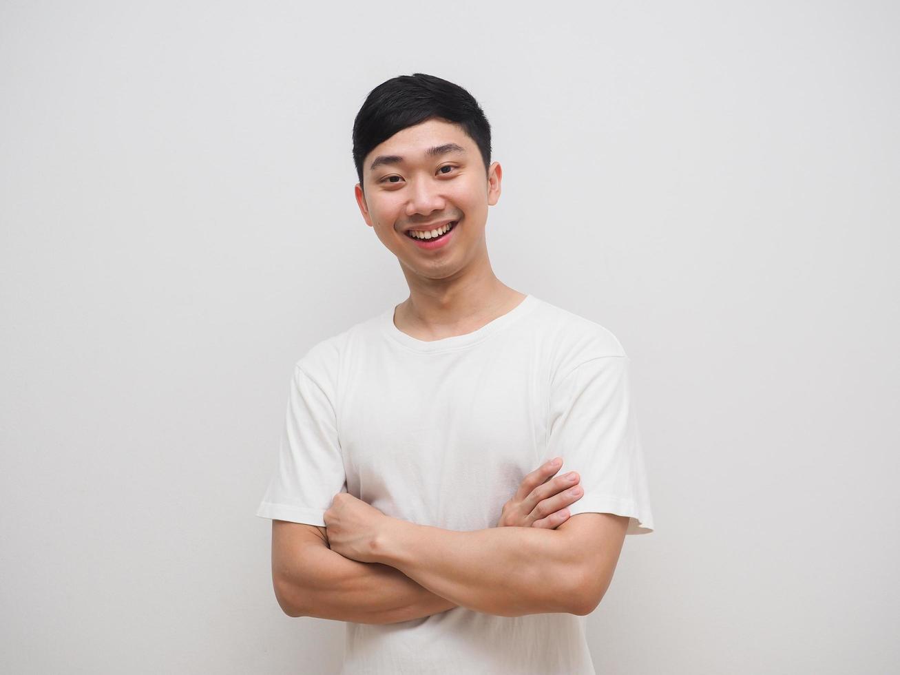 hombre asiático camisa blanca cruza los brazos con una sonrisa feliz y se ríe de la cara sobre fondo blanco isoalte foto