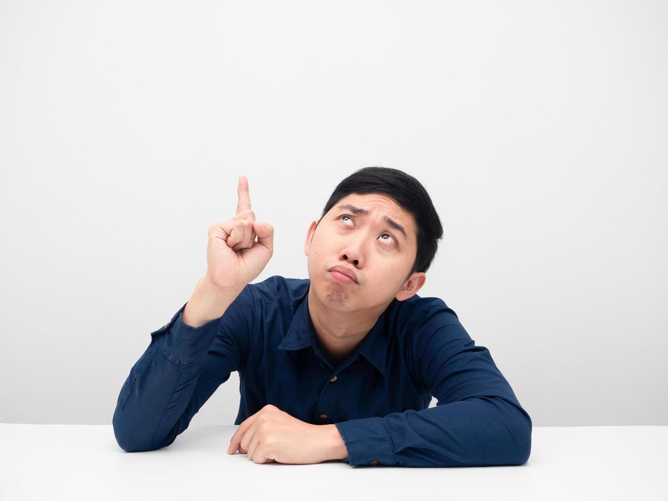 Young man sitting and feeling bored point finger up at copy space photo