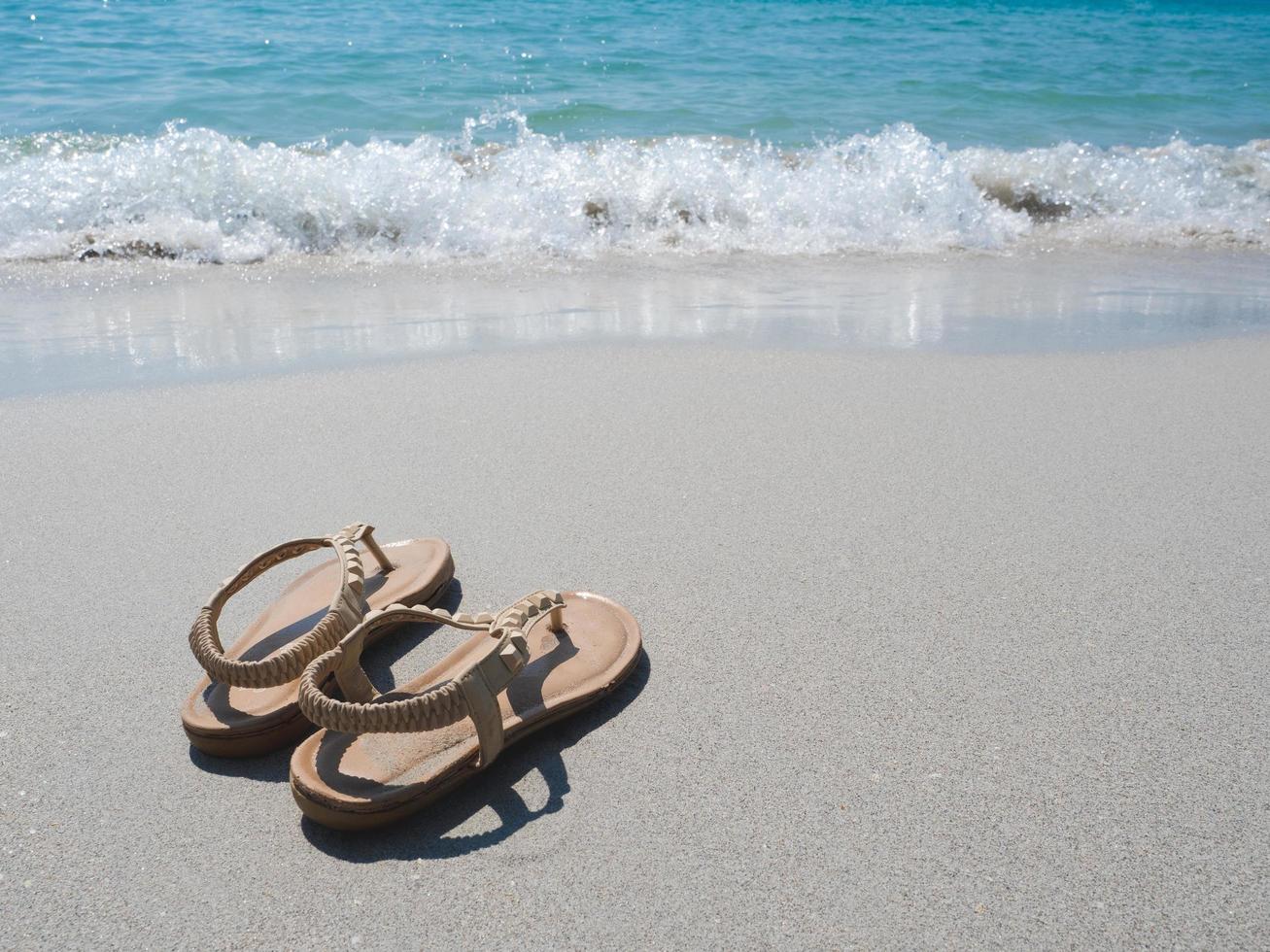 zapato de mujer en la playa y ola de océano azul en natural foto