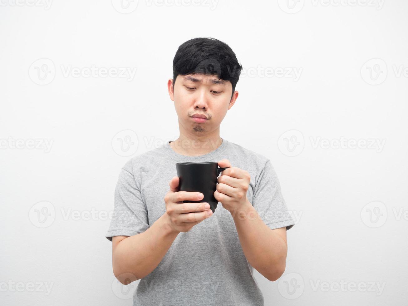 Man looking at coffee cup in his hand feeling bored photo