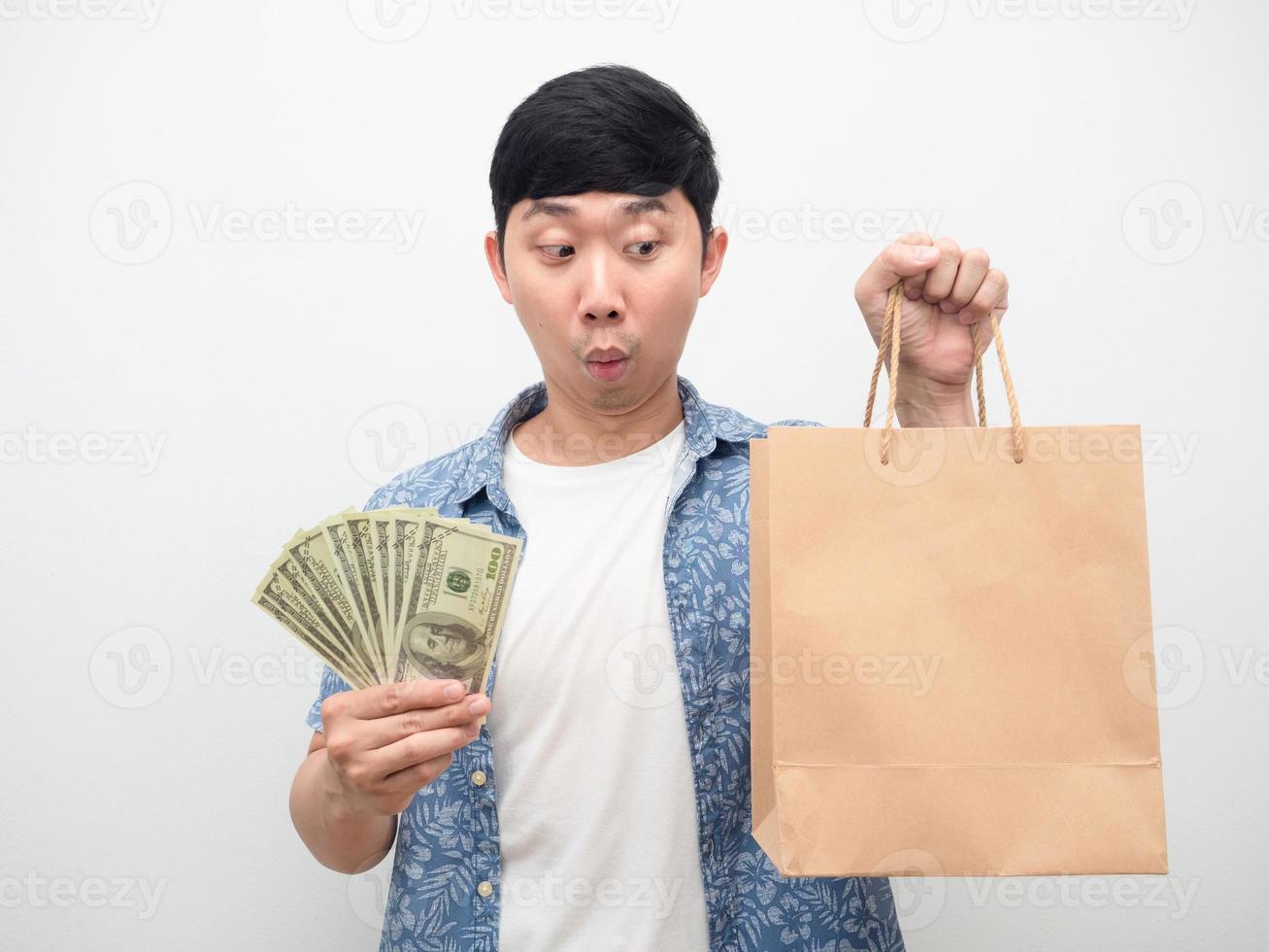 un hombre asiático se siente emocionado sosteniendo un montón de dinero mirando una bolsa de compras en la mano foto