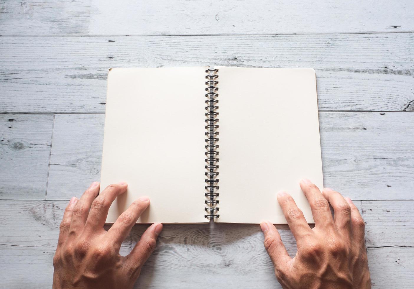 Open book blank page with two hand under on white wood texture background top view photo