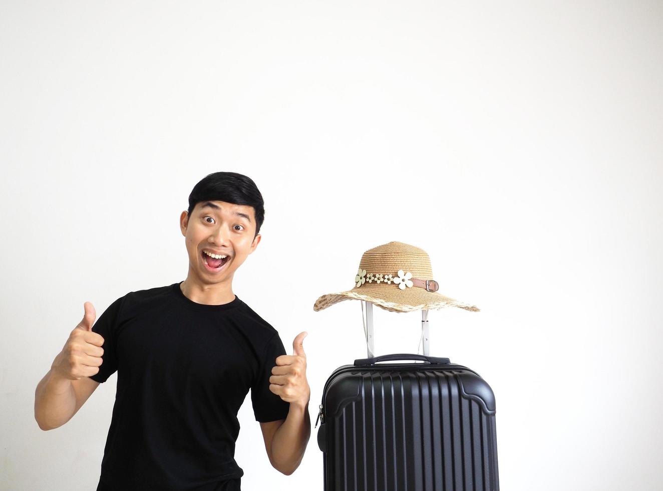 Traveler man black shirt stand and thumps up happy smile excited and vintage hat sunglasses above luggage on white isolated photo