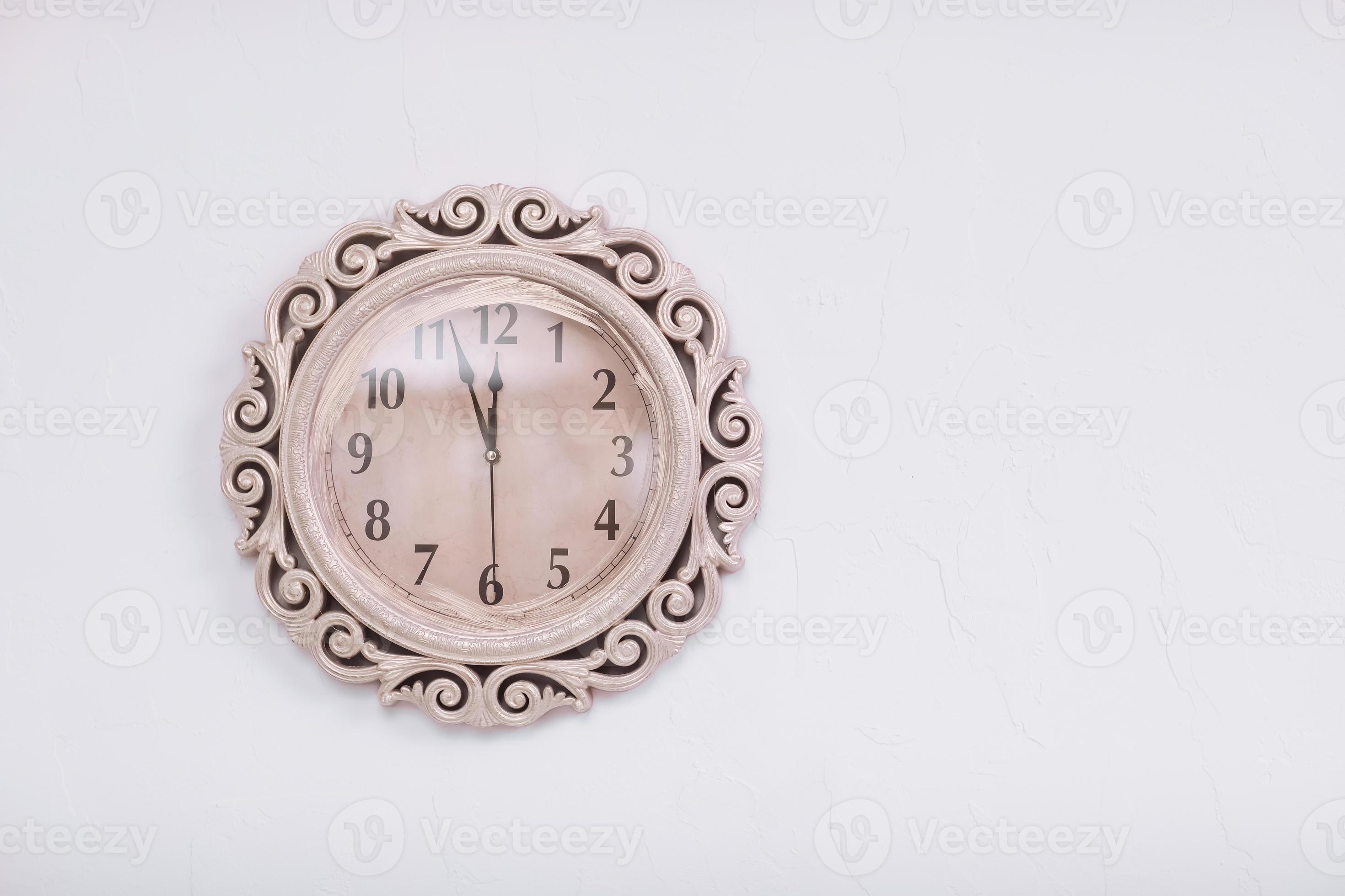classic clock on a white wall background. almost twelve o'clock. eleven
