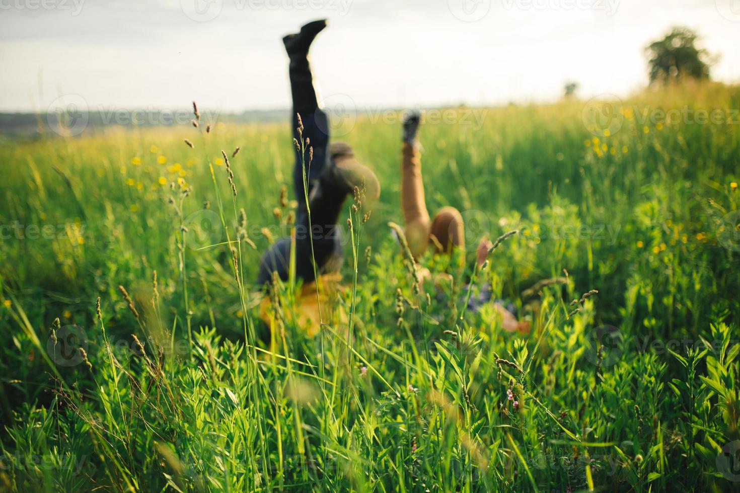 woman and man having fun outdoors. Loving hipster couple walking in the field, kissing and holding hands, hugging, lying in the grass and lifting their legs up in the summer at sunset. valentines day photo