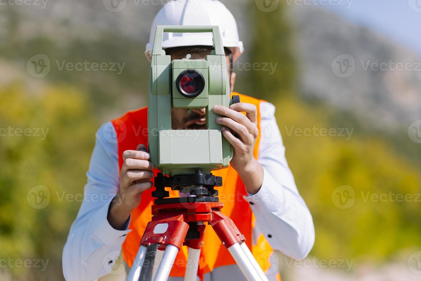 Surveyor engineer is measuring level on construction site. Surveyors ensure precise measurements before undertaking large construction projects. photo