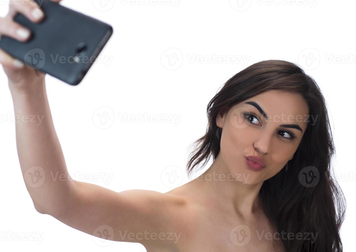 imagen de una hermosa mujer morena riéndose mientras toma una foto selfie en un celular aislado sobre fondo blanco