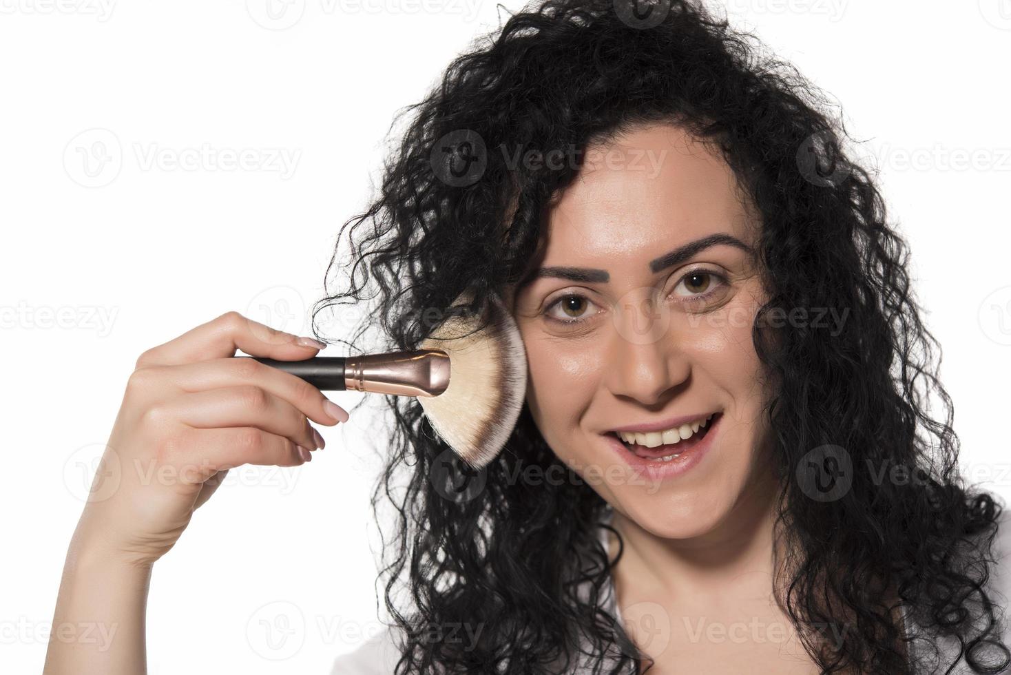 portrait of attractive caucasian smiling woman isolated on white studio shot putting make up in front of mirror photo