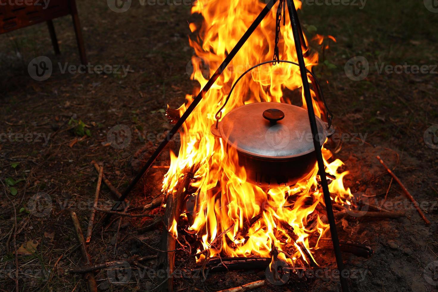 cocinar al aire libre en condiciones de campo. caldero en un incendio en el bosque. cocinar en la hoguera mientras viaja. trípode con un bombín en un fuego en un picnic. viajes conceptuales, trekking y aventura. foto