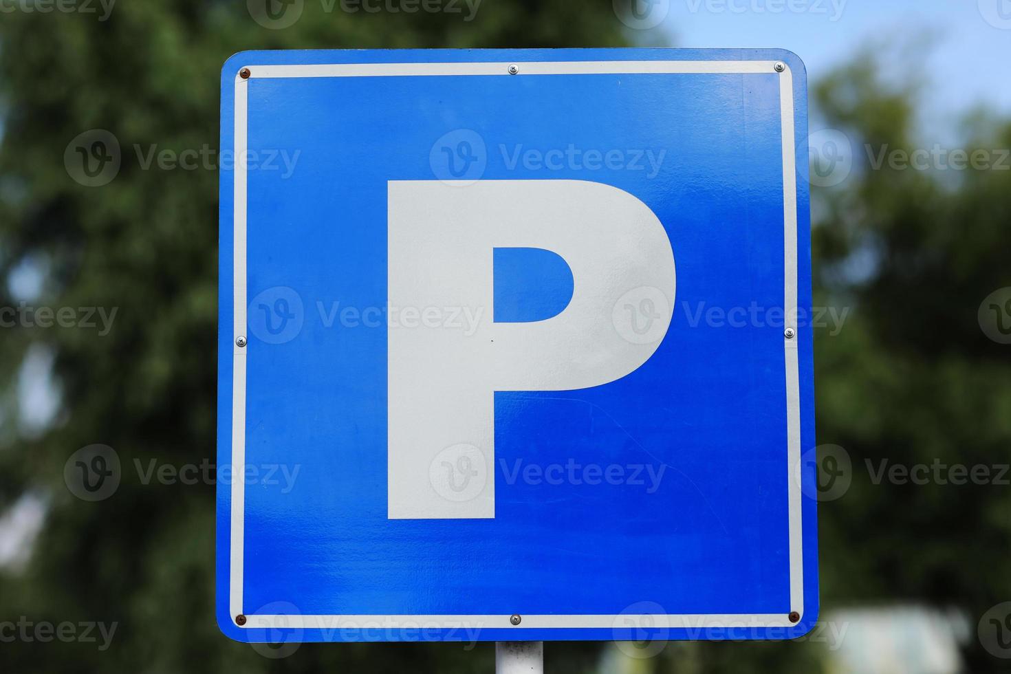 Closeup of a modern free parking sign road sign on nature park background. Isolated parking blue road sign with letter P on rectangular plate photo