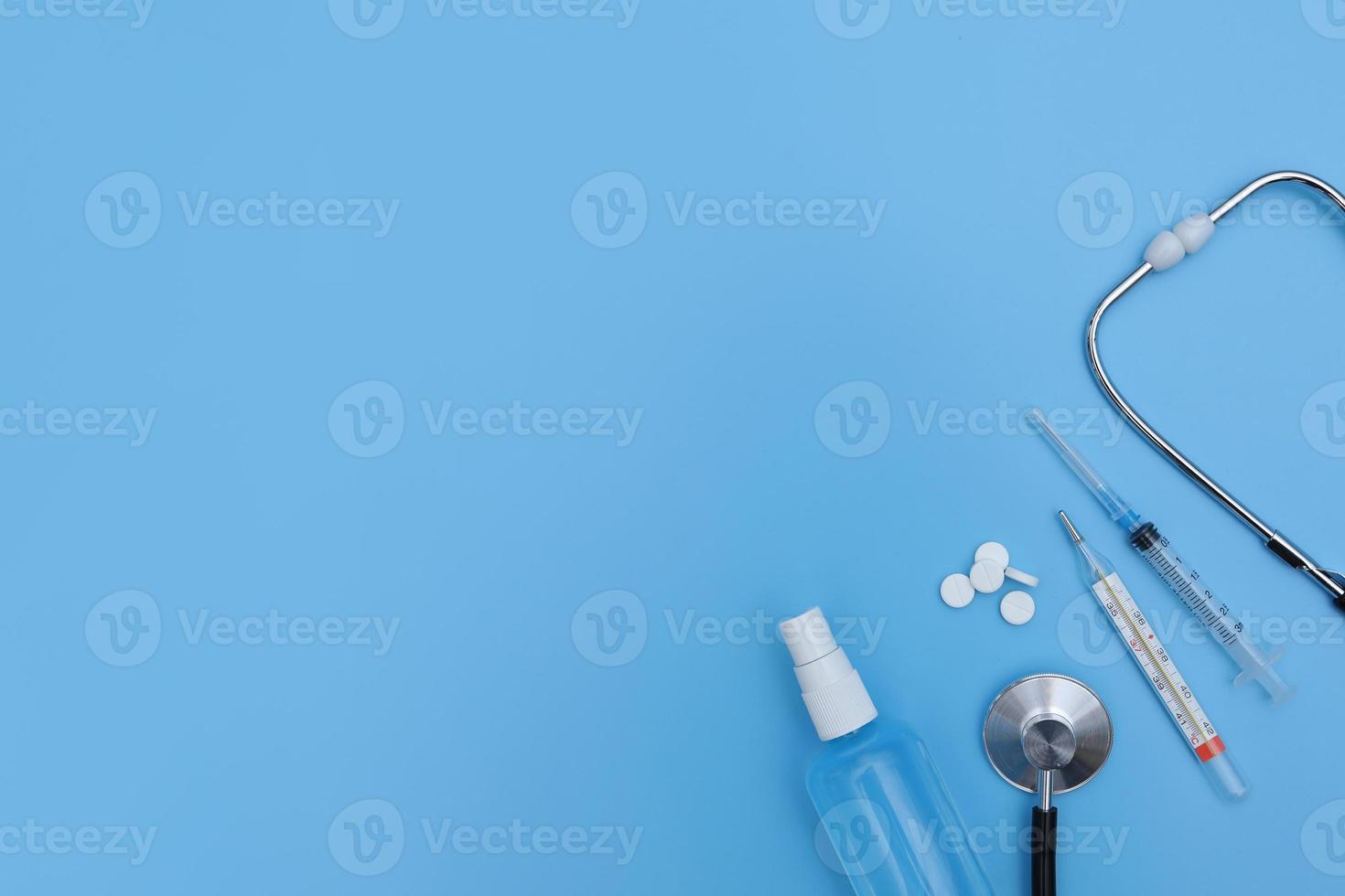 Thermometer, sanitizer, ampoule stethoscope and blister packed medicines over blue backdrop. Concept of healthcare, online shopping, high cost of medicines. expensive medicine. selective focus photo