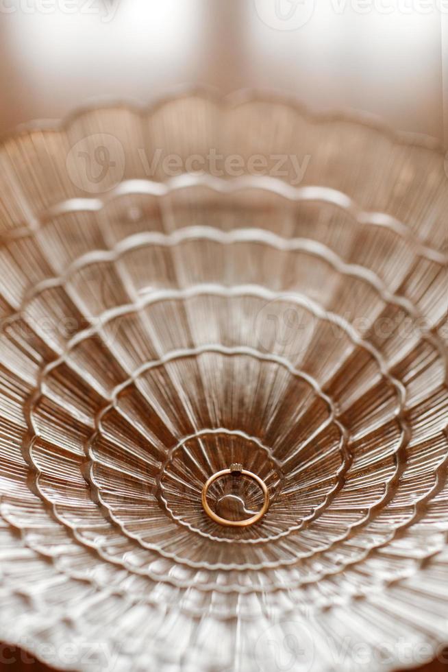 Wedding rings in a beautiful glass. golden engagement ring with diamond in a lace glass bowl background. selective focus photo