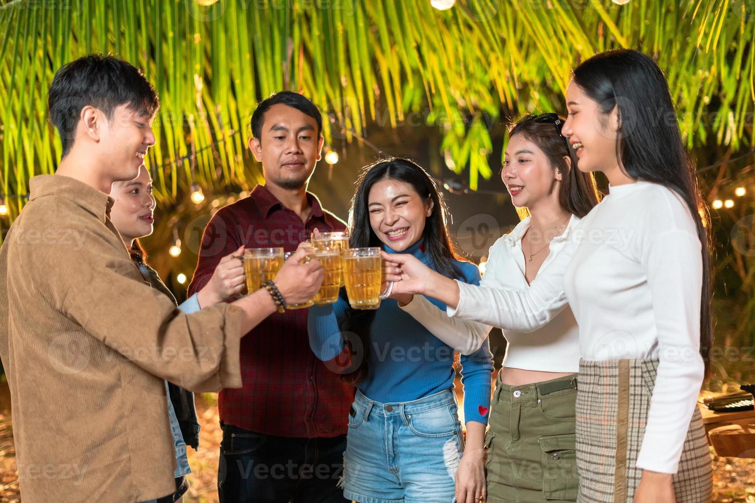 Group of friends happily standing and toasting beers at the party. photo