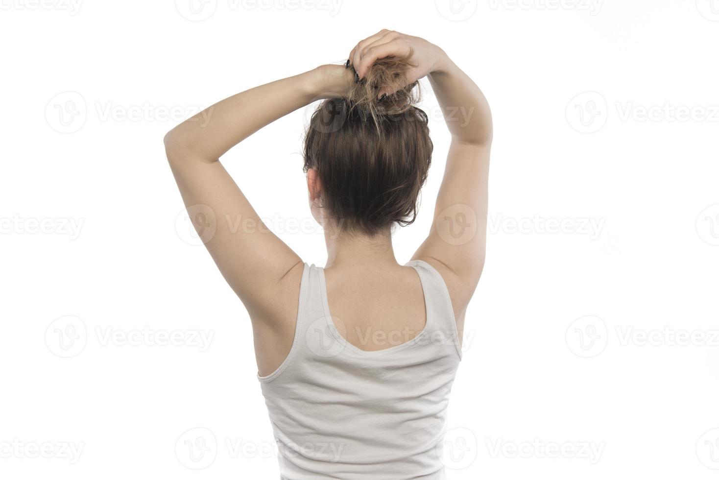 Female model arranging her hair. Woman tying hair in a bun. photo