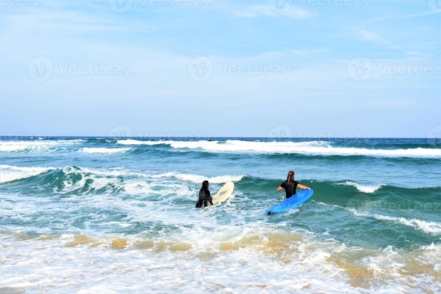 Surfers couple waiting for the high waves on beach - Sporty people with surf boards on the beach - Extreme sport and vacation concept photo