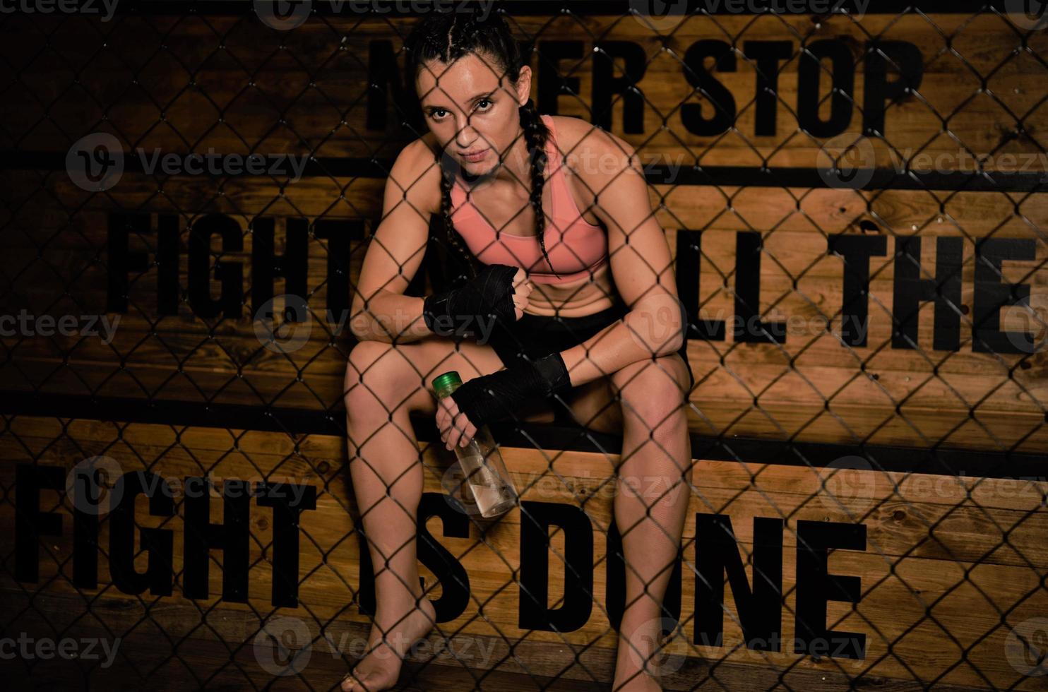 female fighter drinking water and resting after the training. photo