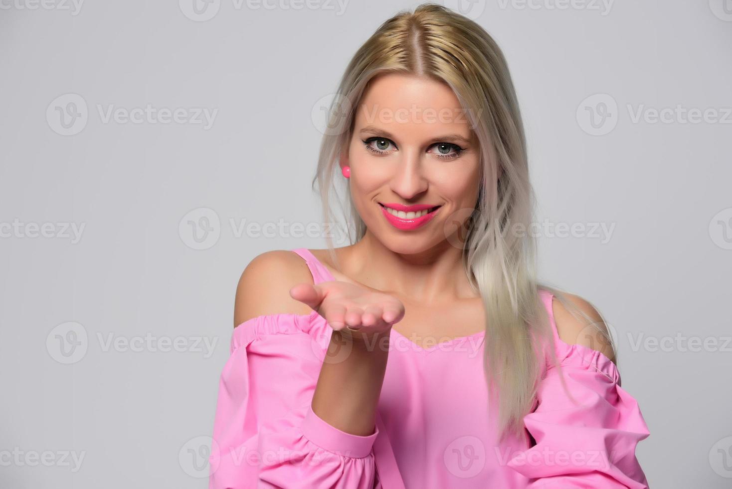 Portrait of beautiful young woman in cute pink shirt and blue jeans posing in studio. Concept of beauty, emotions, facial expression, lifestyle, fashion, youth culture photo
