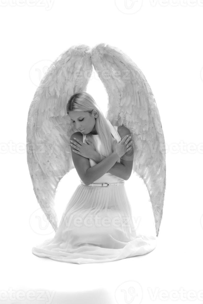 hermosa joven modelo con grandes alas de ángel sentada en el estudio. Fondo blanco foto