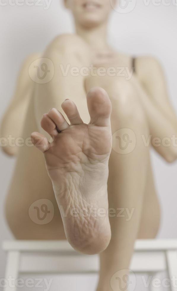 a young woman applies lotion to her feet photo